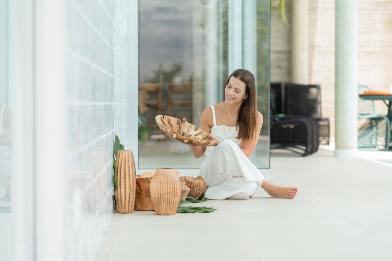 Services-02 A woman in a minimalist setting admires a beautifully crafted wooden decor piece.