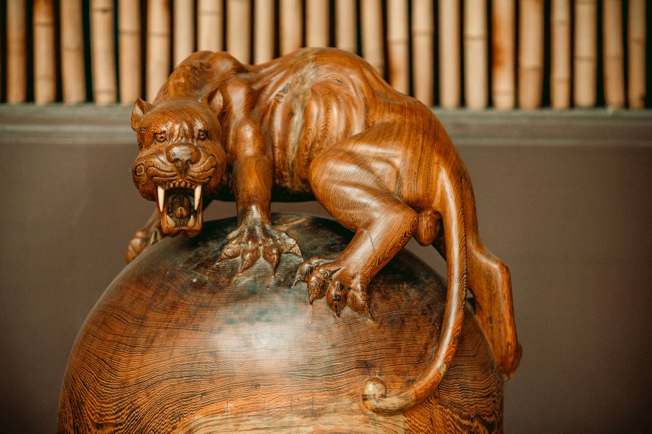 why-choose-us Detailed wooden sculpture of a fierce panther on a sphere, showcasing fine craftsmanship.